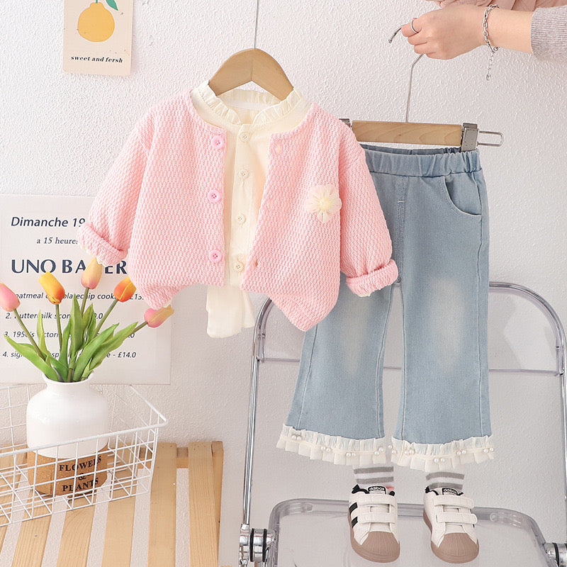 Conjunto de tres piezas , pantalón de jeans con camisa beige y abrigo (suéter) rosa con detalle de moño grande en la espalda