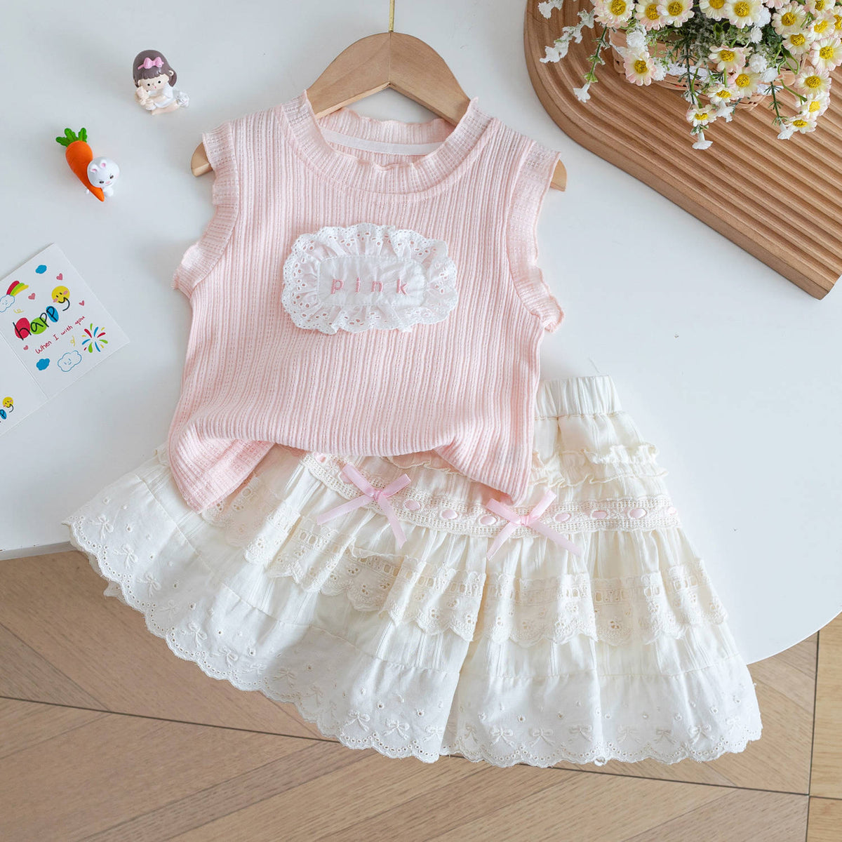 Conjunto pollera marfil forro short con blusa sin manga rosa detalle de broderie y moños